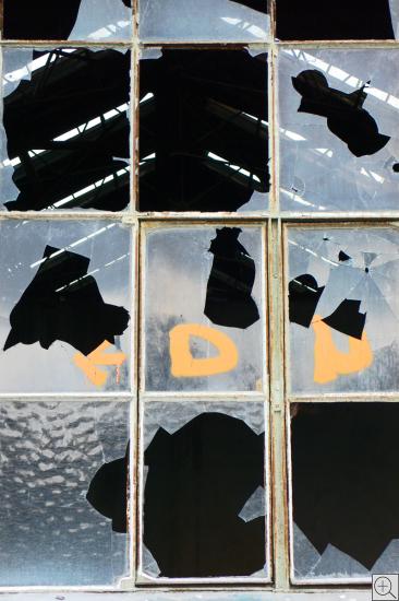 Blick  durch zerbrochenes Fenster eines historischen Industrieensembles