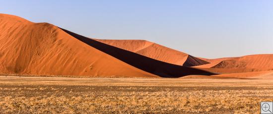 rote Wüstendünen mit scharfen Kanten und tiefen Schatten, abstrakte Landschaft