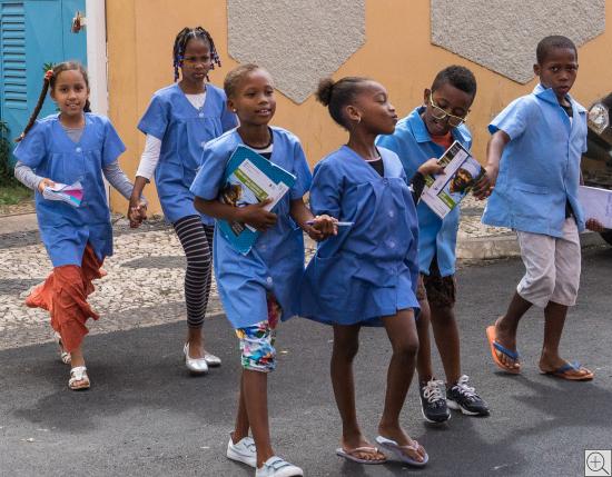6 Schulkinder in hellblauen Uniformen überqueren  die Straße